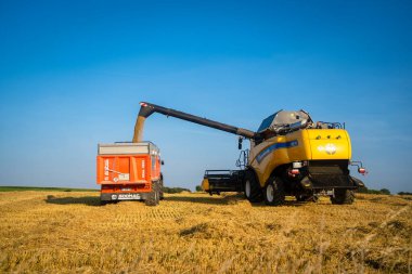 Yeni Hollanda Tarım sarısı, 25 Ağustos 2021 'de Fransa Bratny bölgesinde buğday hasadını birleştirdi. Buğday makası. Sahada birleşiyor. Avrupa 'da tarım temalı sanayi personeli.