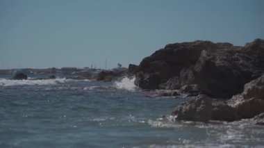 Kıbrıs Rum Kesimi 'nin kayalık bir kıyısında, güneşli yaz havasında Paphos kenti yakınlarında Akdeniz' in dalgaları. Kıbrıs Rum Kesimi Akdeniz 'in berrak zümrüt suyu ve kayalık kıyı şeridi