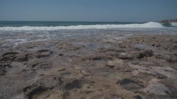 Onde del Mar Mediterraneo su una costa rocciosa a Cipro vicino alla città di Paphos con il tempo estivo soleggiato. Acqua cristallina color smeraldo e costa rocciosa del Mar Mediterraneo, Cipro — Video Stock