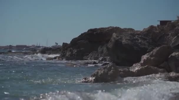 Mořský příboj, modré vlny Středozemního moře na Kypru. Skalnatá kamenitá pláž. Letní den. Slunečný ráj. Slunečný denní plášť. Pohled na pláž na Kypru. Kameny u Středozemního moře — Stock video