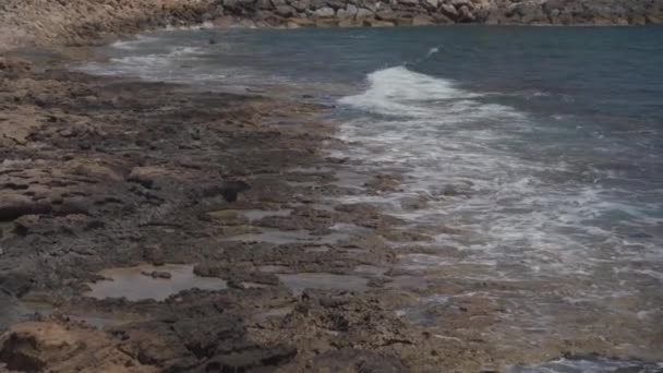 Ondas do Mar Mediterrâneo em uma costa rochosa em Chipre perto da cidade de Paphos em tempo ensolarado verão. Água cristalina esmeralda e costa rochosa do Mar Mediterrâneo, Chipre — Vídeo de Stock