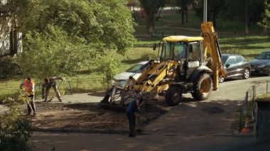 Ukrayna, Kiev, 15 Eylül 2021. Pençeli işçiler asfaltı yoldan çıkarıp kazı kovasına koyuyorlar. Yol onarımı ağır iş. Kürek işçileri eski asfaltın yerini aldı