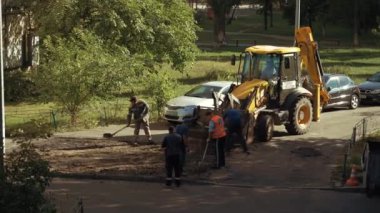 Ukrayna, Kiev, 15 Eylül 2021. Pençeli işçiler asfaltı yoldan çıkarıp kazı kovasına koyuyorlar. Yol onarımı ağır iş. Kürek işçileri eski asfaltın yerini aldı