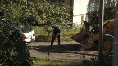 Ukrayna, Kiev, 15 Eylül 2021. Pençeli işçiler asfaltı yoldan çıkarıp kazı kovasına koyuyorlar. Yol onarımı ağır iş. Kürek işçileri eski asfaltın yerini aldı