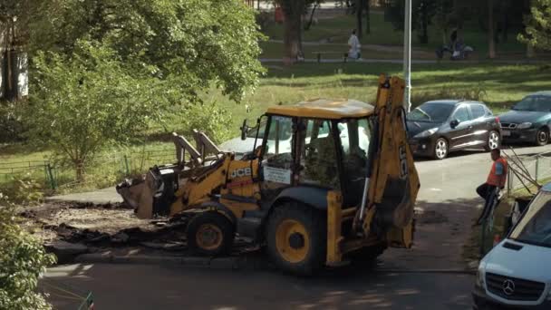 Ucrania, Kiev, 15 de septiembre de 2021. Los trabajadores retiran el asfalto colocándolo en el cubo de la excavadora. Bulldozer con grupo de trabajadores durante las obras de carretera en una carretera asfaltada. Construcción de carreteras — Vídeo de stock