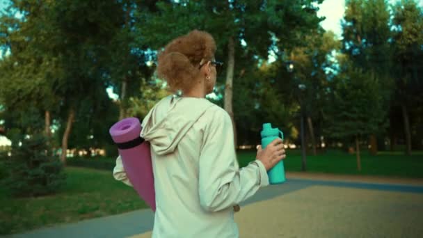 Happy senior woman going on sport training, carry yoga mat. Saúde e desporto. Joyful fêmea madura com esteira indo praticar exercícios de ioga ao ar livre. Desportista idosa transportando tapete laminado para a aptidão — Vídeo de Stock