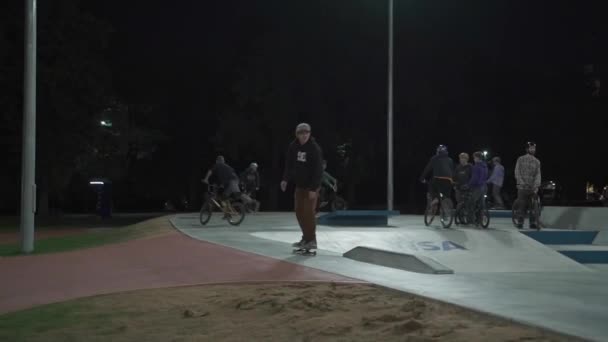 Ucrania, Kiev, 18 de septiembre de 2021. Parque Urbano. Skateboarders, ciclistas bmx y niños en scooters deportivos hacen trucos en el parque de skate de la ciudad por la noche. Deportes extremos, amistad, juventud, concepto de estilo de vida — Vídeos de Stock