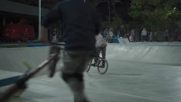 Ucrânia, Kiev, 18 de setembro de 2021. Parque Urbano. Skatistas, ciclistas bmx e crianças em scooters esportivos fazem truques no parque de skate da cidade à noite. Esporte extremo, amizade, juventude, conceito de estilo de vida — Vídeo de Stock