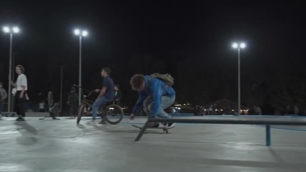 Ukrajina, Kyjev, 18. září2021. Městský park. Teenage skateboardisté, bmx cyklisté, sportovní skútry vlak, dělat triky, skok do městského skateparku ve večerních hodinách. Zdravý životní styl, extrémní sporty, redakční — Stock video