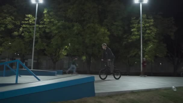 ウクライナ、キエフ、 2021年9月18日。都市公園。ライトスポットライトで夜の屋外スケートパークでストリートスケートボード。外のスケートパークでの極端なスケート。スケートボーダー、 bmxと公園のスクーター — ストック動画