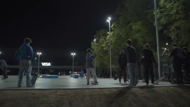 Ukrajina, Kyjev, 18. září2021. Městský park. Skateboardisté, bmx cyklisté a děti na sportovních skútrech dělat triky v městském skate parku ve večerních hodinách. Extrémní sport, přátelství, mládež, životní styl koncepce — Stock video