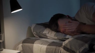 Genç beyaz adam yatakta dönüyor, rahatsız uyku koşulları. Sinirli adam geceleri uyuyamaz, uykusuzluk. Duygusal ve uyku bozuklukları konsepti. Erkek buluşması şafakta yatakta