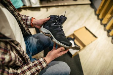 Beyaz adam bir spor ve seyahat mağazasında yürüyüş ayakkabısı seçer ve ölçer. Dışarıdaki dükkanda yürüyüş ayakkabılarına bakan bir adam. Spor mağazasında erkek yürüyüş botları. Seyahat malları depolama teması.