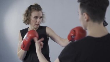 Dövüş sanatları tekvando eğitimi ve kişisel antrenman sırasında bayan öğrenci. Pençelerini kullanarak antrenman yapan kadın antrenör. Sporcu yumruk yumruğa, antrenman koçuna yumruk atar..