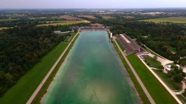 Luftbild des Olympischen Regattazentrums Muenchen, Deutschland. Ruder-und Kanusport, Tribuene, Juryturm, Gruene Landschaft, Nachhaltige Mimarlık ve Olimpiyatlar.