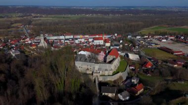 Drohnenaufnahme von Burg Tittmoning, Klosterkirche der Augustiner und Altstadt mit mittelalterlicher Stadtmauer. Aufgenommen a einem sonnigen Fruehlingstag. 