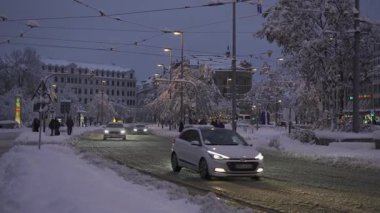 20 Aralık 2024. Münih, Almanya. Muenchen 'de karlı bir akşam, yoğun kar yağışı sokakları, arabaları ve ağaçları kaplıyor. Şehir ışıkları parlıyor, trafik yavaş ilerliyor. Karlsplatz rekor kıran karla kaplıdır.. 
