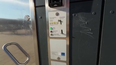 Donauwoert, Almanya 'daki umumi tuvaletin yakın çekimleri, metal kapıyı, ödeme için bozuk para yuvasını ve modern, temiz tasarımı ile tuvaletin dış yüzeyinin bir kısmını gösteriyor..