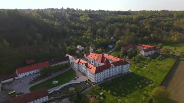 Kloster Schaeftlarn ve Praelatengarten 'in hava aracı görüntüsü, bir Barok Benedictine manastırı ve Almanya' nın Bavyera kentindeki resmi bahçe. Çevresi yeşil tepeler, ormanlar ve kırsal manzaralarla çevrili
