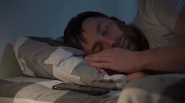 30 'lu yaşlarında yorgun ve sinirli bir adam ekose çarşafların altında uykusuzlukla boğuşuyor. Gözlerini ovuşturuyor, telefonundaki saati kontrol ediyor, uykusuzluk ve gelecek iş günü yüzünden hayal kırıklığına uğruyor..