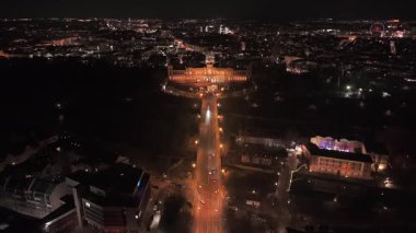 Drohnenperspective bei Nacht ueber Maximilianeum, Sitz Bayerischen Landtag in Muenchen. Die erhellte Fassade und das Isarufer im Vordergrund verleihen der Szene eine eine Beeindruckende Abendatêhaere