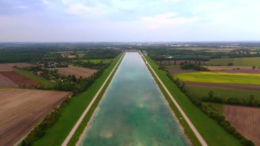Olympic Regatta Center, Münih, Almanya. Tribünlerle, jüri kulesiyle ve doğa ve çayırlarla çevrili manzaralı düzlüklerle dolu havadan drone görüntüsü..