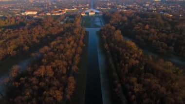Aralık 'ta gün batımında Schloss Nymphenburg' un hava manzarasında su kanalı, ağaç hatları ve kış manzarası yer almaktadır. Drone perspektifi Bavyera ikonik barok sarayını ve görkemli park caddelerini gösteriyor