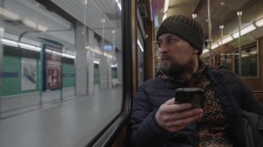Muenchen 'de eski bir U-Bahn arabasının içinde bir gezginin yaşam tarzı fotoğrafı. Akıllı telefonu olan bir adam, yarısı boş bir vagonda dijital içeriğe bakıyor. Alman mirası taşımacılığı.