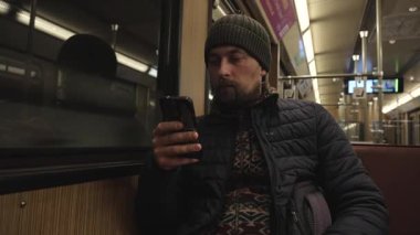 U-Bahn Muenchen 'in eski model bir arabasında akıllı telefon kullanan bir adam. Baureihe marka, içi ahşap kaplamalı bir arabada oturuyor. Almanya, Bavyera 'da otantik toplu taşıma.