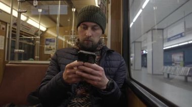 Baureihe A treninin içindeki akıllı telefonu kullanan bir banliyö. Geleneksel ahşap kaplama Muenchen metro vagonunun içi. Almanya, Bavyera 'nın kalbindeki günlük yaşam ve hareketlilik.