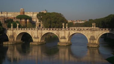 Ponte SantAngelo 'nun Roma, İtalya' daki Tiber Nehri 'ni geçişi ve arkasında Castel SantAngelo' nun olduğu manzara. Roma şehir merkezinde tarihi bir köprü ve önemli bir turistik ilgi merkezi..