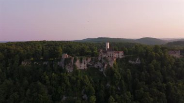 Lichtenstein Şatosu, altın saat ile yukarıdan. Almanya 'nın Honau şehrinde yer alan bu tarihi şato, Swabian Jura üzerinde çarpıcı bir günbatımı manzarası sunmaktadır. Kale bir uçurumun üzerinde. Marchenschloss Wurttembergs.