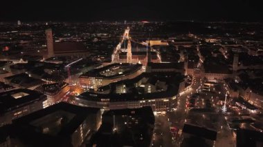 Marienplatz, Frauenkirche, Alter Peter Tower ve kış tatili sezonunda parlayan Noel pazarlarının yer aldığı Münih şehir merkezi Bavyera 'da geceleyin sinematik dron görüntüleri.