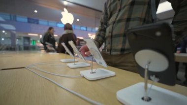 2 Ekim 2025. Münih, Almanya. Müşteri, modern perakende ve akıllı telefon teknolojisini sembolize eden hareketli resmi Apple Store 'da son teknoloji Apple iPhone ile etkileşime geçiyor.