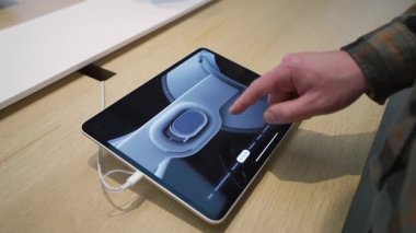 2 Ekim 2025. Münih, Almanya. Apple Vision Pro 'yu araştıran adam Almanya' daki Apple Store 'da bir tablet hakkında bilgi topluyor. Ekranda Almanca metin var. Apple 'ın karışık gerçeklik teknolojisini gösteren modern perakende alanı