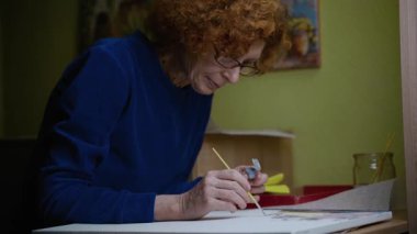 Yaş, emeklilik, yaratıcılık, hayal gücü ve sanat. Yaratıcı çalışma. Beyaz dişiler karantina sırasında yağlı boya ve fırçayla tuvale resim çizer ve Coronavirus 'u kilitler..