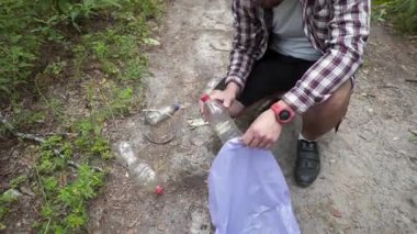 Güvenli gezegen, sırt çantalı insan yürüyüşçüsü doğada yürürken temiz gezegen, çevre ve ekoloji için ormandaki plastik çöp torbalarında çöp topluyor. Yeşil gönüllü. Adam eli çöp topluyor..