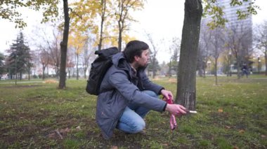 Sonbaharda şehir parkında kaçak bir köpek arayan genç beyaz bir adam elinde bir yem tutuyor ve evcil hayvan istiyor. Şehirdeki insanlar ve evcil hayvanlar teması. İtaatkar bir köpek bulmak.