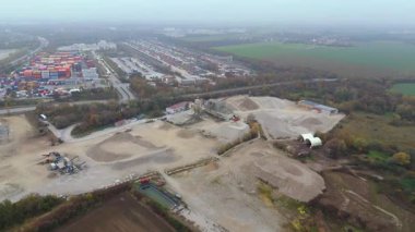 Endüstriyel bölgelerle çevrili Almanya 'daki aktif kum ocağının havadan görüntüsü. Ağır makineler sisli sonbahar atmosferinde çalışır, ham, endüstriyel manzarayı ve devam eden çıkarma çalışmalarını vurgular..