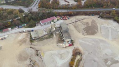 Endüstriyel bölgelerle çevrili Almanya 'daki aktif kum ocağının havadan görüntüsü. Ağır makineler sisli sonbahar atmosferinde çalışır, ham, endüstriyel manzarayı ve devam eden çıkarma çalışmalarını vurgular..
