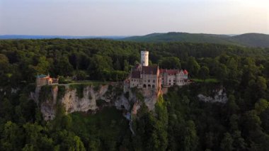 Schloss Lichtenstein 'in insansız hava aracı görüntüsü, Almanya' nın Baden-Wuerttemberg eyaletinin Honau kentinde 19. yüzyıldan kalma bir uçurum kenarı şatosu. Gün batımında Echaz Vadisi ve Swabian Alpleri 'ne bakan altın ışıkta ele geçirildi..