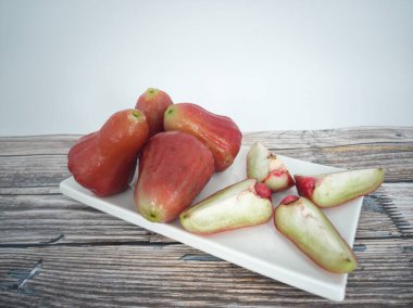 Dilimlenmiş bir gül elması ve jambu havası, balmumu elma ve beyaz tabakta chomphu olarak da bilinen bir kaç meyve. Seçici odak noktaları.