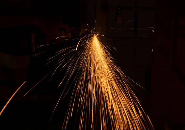 Close-up of sparks from cutting metal with the electrical saw. Selective focus points. Blurred background