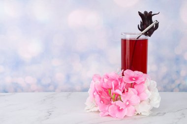 Bir bardak Roselle, metal saman ve çiçekle içer.