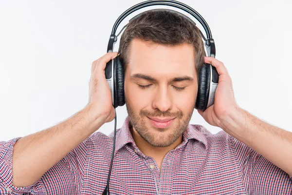 Sonriente hombre escuchando música en auriculares con los ojos cerrados — Foto de Stock