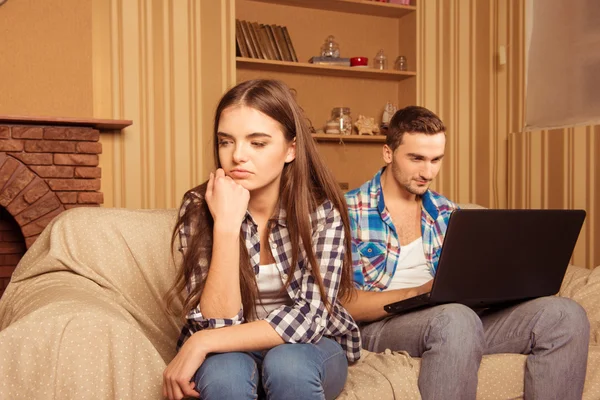 Hombre alegre sirviendo Internet en el ordenador portátil ignorando a su novia —  Fotos de Stock