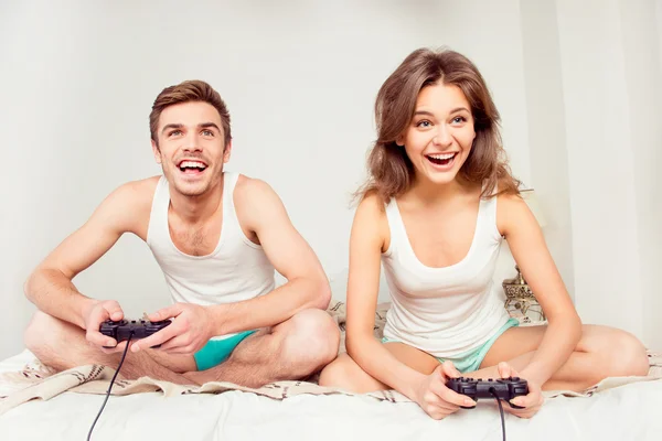 Schattig paar in liefde spelen video games met joysticks op de be — Stockfoto