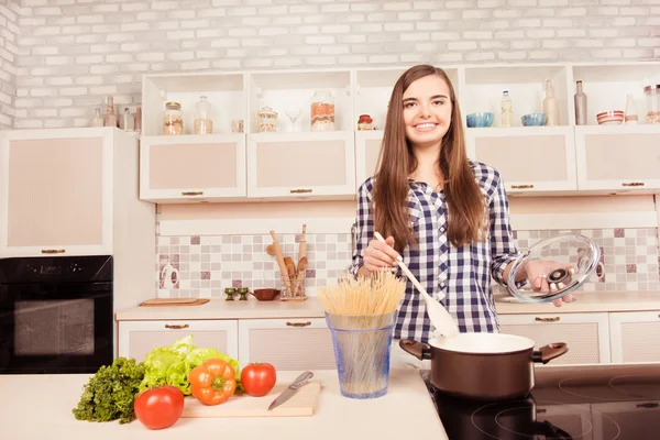 Gelukkig lachende jonge vrouw koken in de keuken — Stockfoto