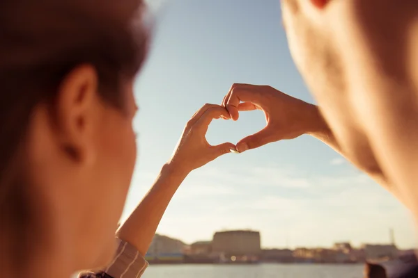 Picture of romantic couple  gesturing a heart with fingers on th — Stock Photo, Image