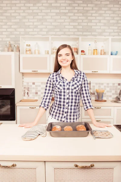 Vrolijke vrouw glimlachend in de keuken met gebakken brood — Stockfoto